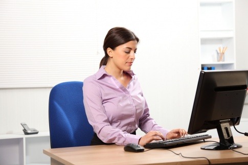 Eine Frau, die aufrecht an ihrem Schreibtisch sitzt