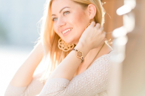 Eine blonde Frau trägt ein Armband und Ohrringe aus Holz