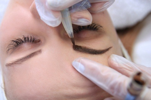 Eine Frau lässt sich die Augenbrauen mit Permanent Make up vom Profi verschönern