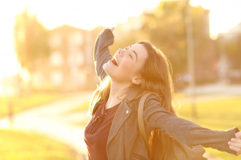 Bedürfnis nach Selbstverwirklichung - junge Frau ist glücklich und losgelöst, will die Sonne umarmen.