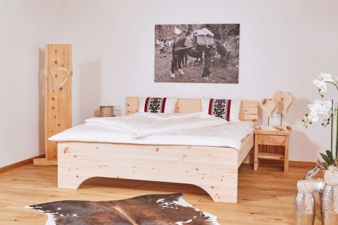 Ein Schlafzimmer mit einem Bett aus Zirbenholz ist aufgeräumt