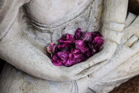 Buddha Statue mit Blüten als Zeichen für Kinderwunsch