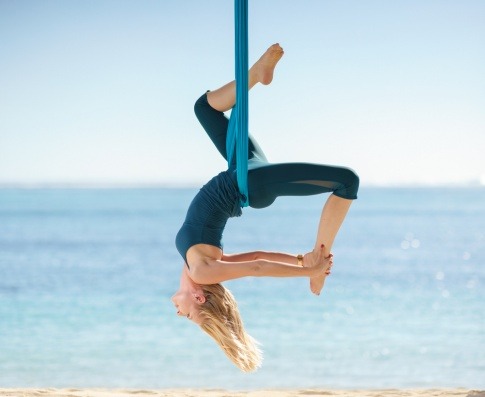 Eine junge Frau betreibt Flying Yoga am Meer