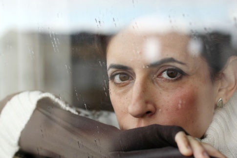 Eine Frau sieht traurig und nachdenklich aus dem Fenster