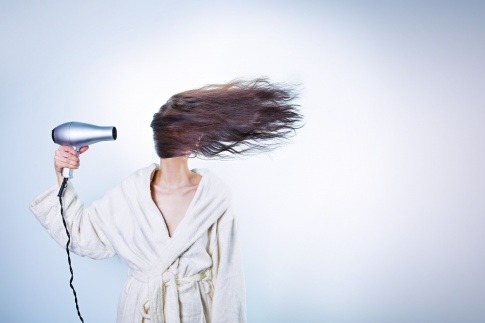 Eine Frau föhnt ihre Haare mit einem Föhn