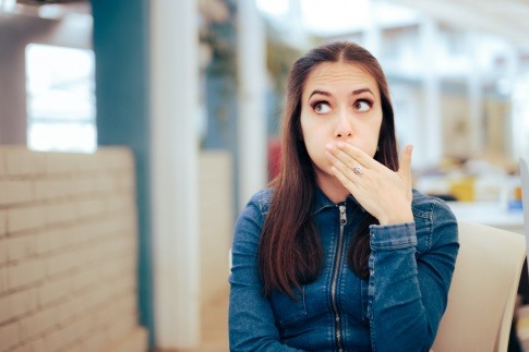 Frau hält Hand vor Mund wegen häufigen Aufstoßen nach dem Essen
