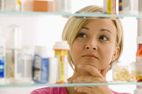 Frau betrachtet die Medikamente in ihrer Hausapotheke