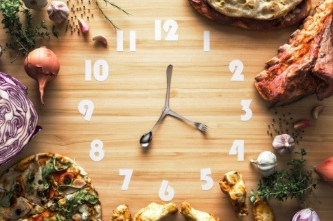 Auf einer Uhr sind Nahrungsmittel als Symbol für Intervallfasten