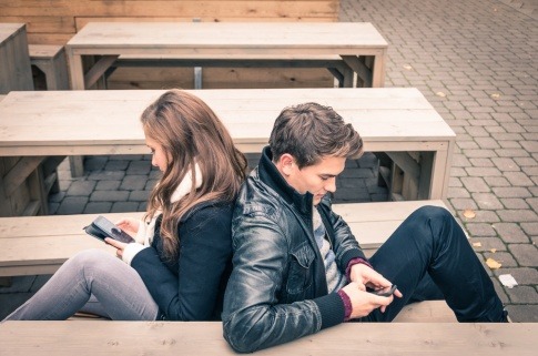Keine Gemeinsamkeiten - Beziehung auf Abruf? Paar sitzt Rücken an Rücken auf dem Sofa, beide beschäftigen sich mit ihrem Smartphone.