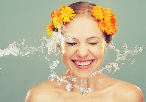 Eine Frau spritzt zur Körperpflege Wasser ins Gesicht