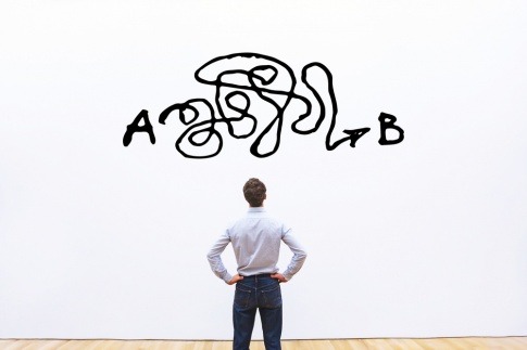 Warum sind Männer so kompliziert? Ein Mann steht vor einer Wand, auf die ein verwirrendes Muster gedruckt ist.