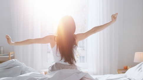 Eine Frau streckt sich im Bett nach dem Aufwachen