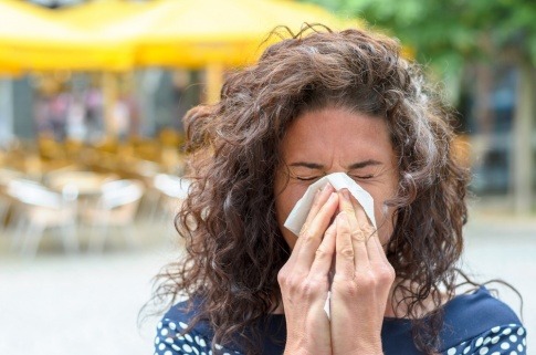 Frau niest in ein Taschentuch wegen Heuschnupfen
