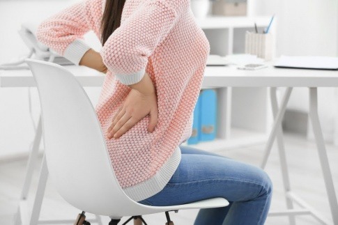 Frau mit Rückenschmerzen, sitzend