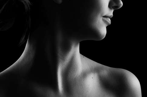 Eine Frau zeigt ihren Hals, wo die Schilddrüse sitzt