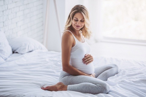 Eine schwangere Frau sitzt im Bett