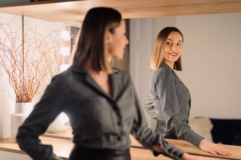 Eine Frau sieht sich voll Selbstliebe in den Spiegel