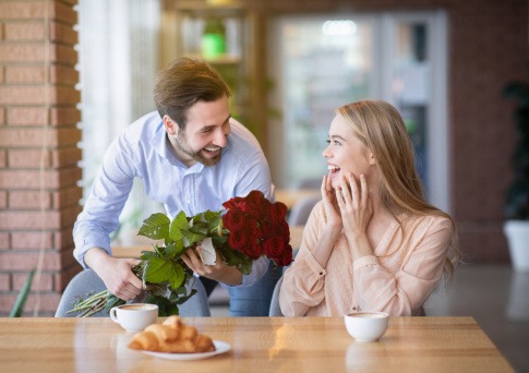Mann schenkt einer Frau rote Rosen als Zeichen der Liebe