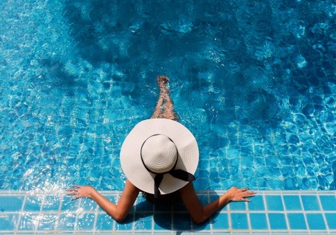 Frau mit Hut am Rand des Pools