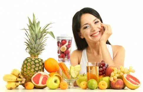 Eine Frau sitzt vor Obst und will Vitamine für Kosmetik