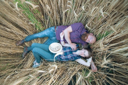 Was macht eine Beziehung aus? Ein glückliches Paar liegt in einem Feld mit hohem Gras und kuschelt.