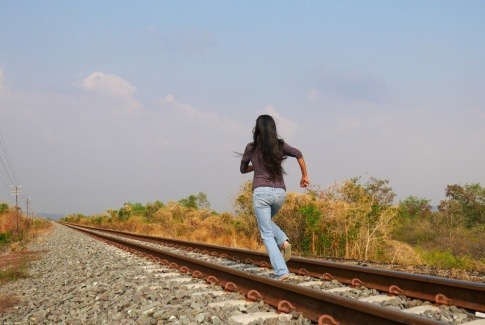 Eine Frau will auf Bahngleisen vor Problemen weglaufen.