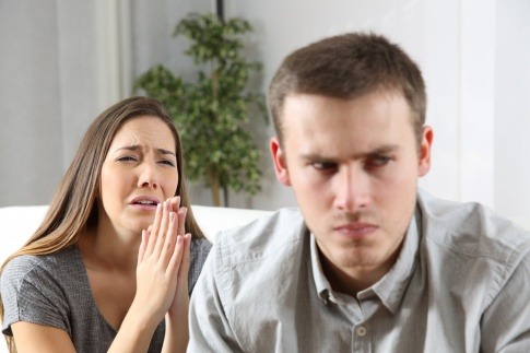 Eine Frau weint und bittet einen ihr abgewandten Mann verzweifelt um Vergebung