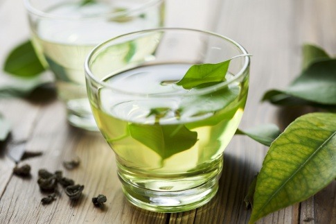 Grüne Blätter liegen in einer Tasse mit grünem Tee