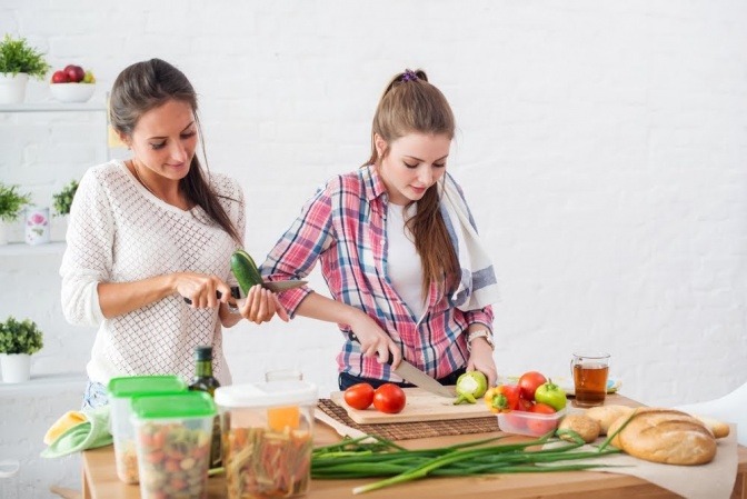 Zwei Frauen bereiten gemeinsam eine Mahlzeit aus gesunden Zutaten zusammen.
