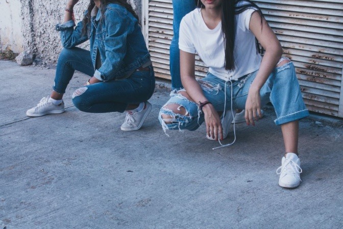 Zwei Frauen tragen jeweils eine kürzer geschnittene Jeanshose