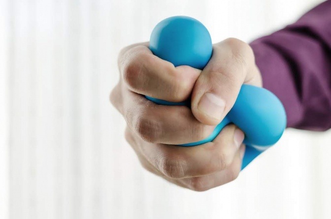 Eine menschliche Hand knetet einen blauen Stressball.