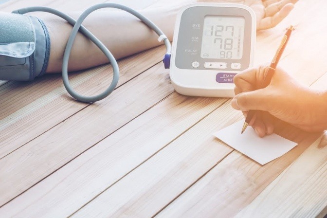 Eine Person misst ihren Blutdruck mit einem digitalen Blutdruckmessgerät.