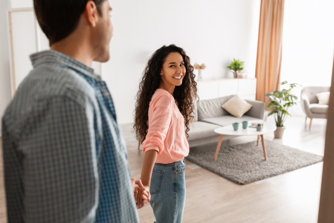 Eine Frau geleitet einen Mann in eine Wohnung, sich fragend wann ist eine Beziehung eine Beziehung?