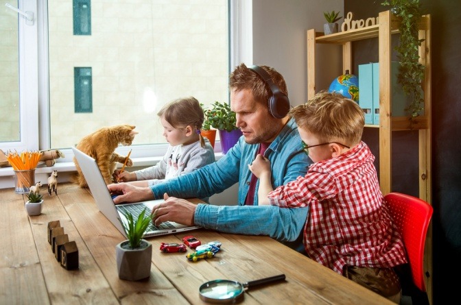 Mann bei der Arbeit im Homeoffice, die Kinder stören.