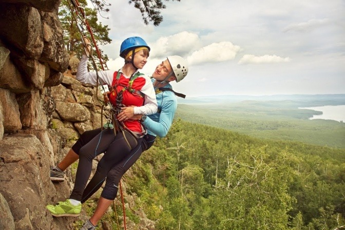 Ein junges Paar hängt gesichert in einer Felswand. 