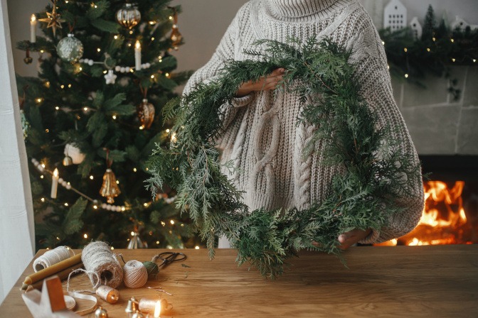 Frau hält Adventskranz aus Tannenzweigen in den Händen