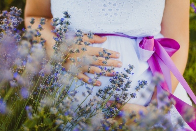 Eine Frau mit Schwangerschaft steht in einem Feld mit Lavendel