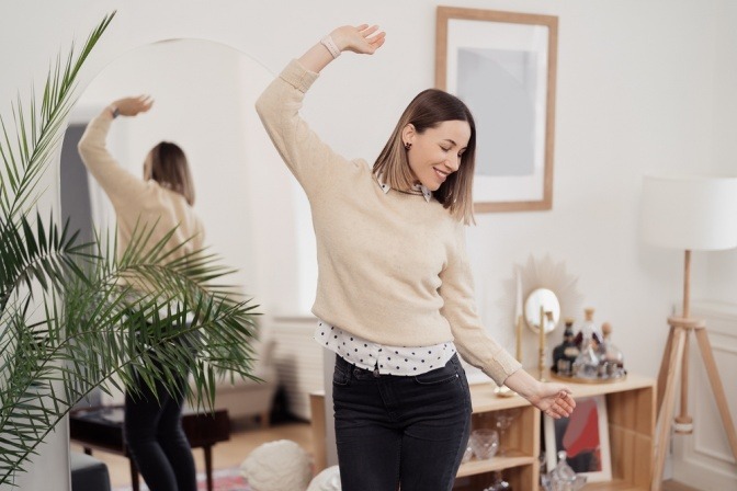 Frau hat durch Affirmationen für Selbstliebe neue Lebensfreude und tanzt in ihrer Wohnung