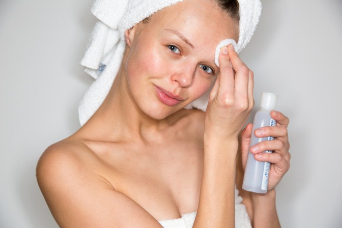 Eine junge Frau reinigt ihre Haut im Gesicht