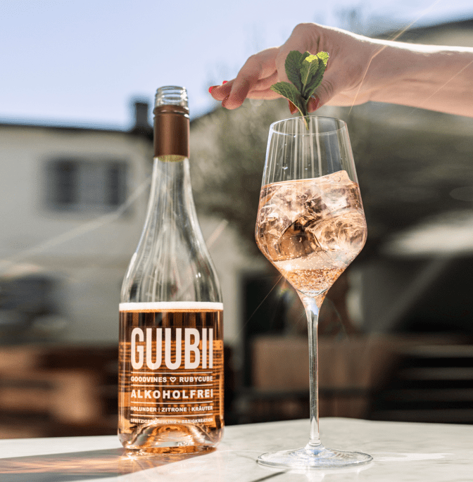 Flasche mit alkoholfreiem Aperitif GUUBII steht neben einem Glas