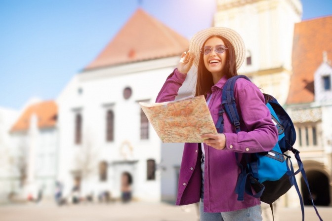 Lächelnde Touristin liest eine Karte.