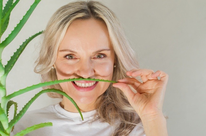 Frau mit unreiner Haut hält Aloe-Vera-Blatt