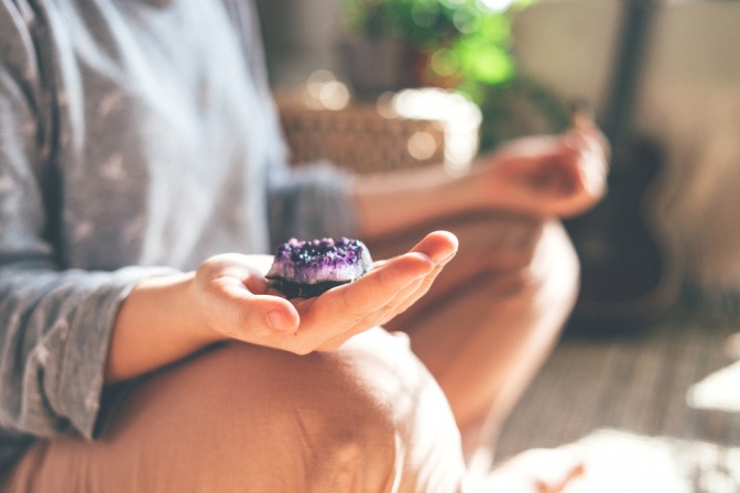 Frau bei der Meditation mit Amethyst in der Hand