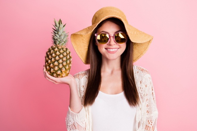 Frau mit Ananas, guter Laune und Sonnenbrille