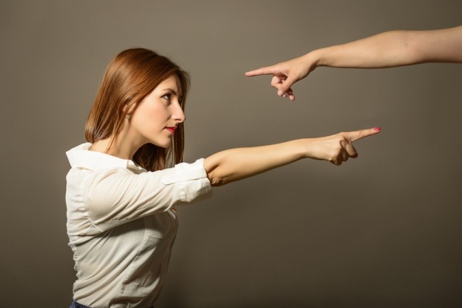 Junge Frau zeigt mit Finger auf jemand anderen und macht diese Person für Probleme verantwortlich.