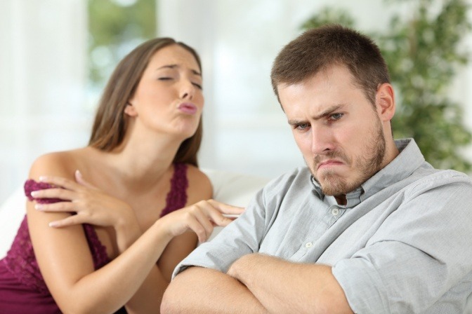Ein Mann schmollt vor sich hin, während seine Partnerin ihm ein eindeutiges Angebot macht.