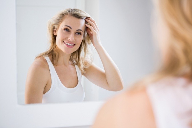 Eine Frau schaut in den Spiegel und benötigt Anti-Aging Serum für Falten
