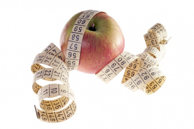 Maßband rund um einen Apfel als Symbol für Gesundheit