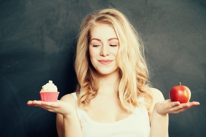 Eine Frau hält einen Apfel und einen Muffin