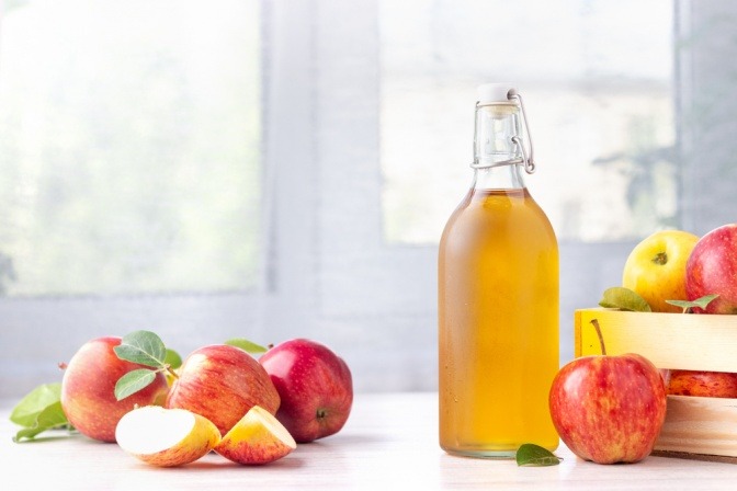 Apfelessigflasche und frische Äpfel.
